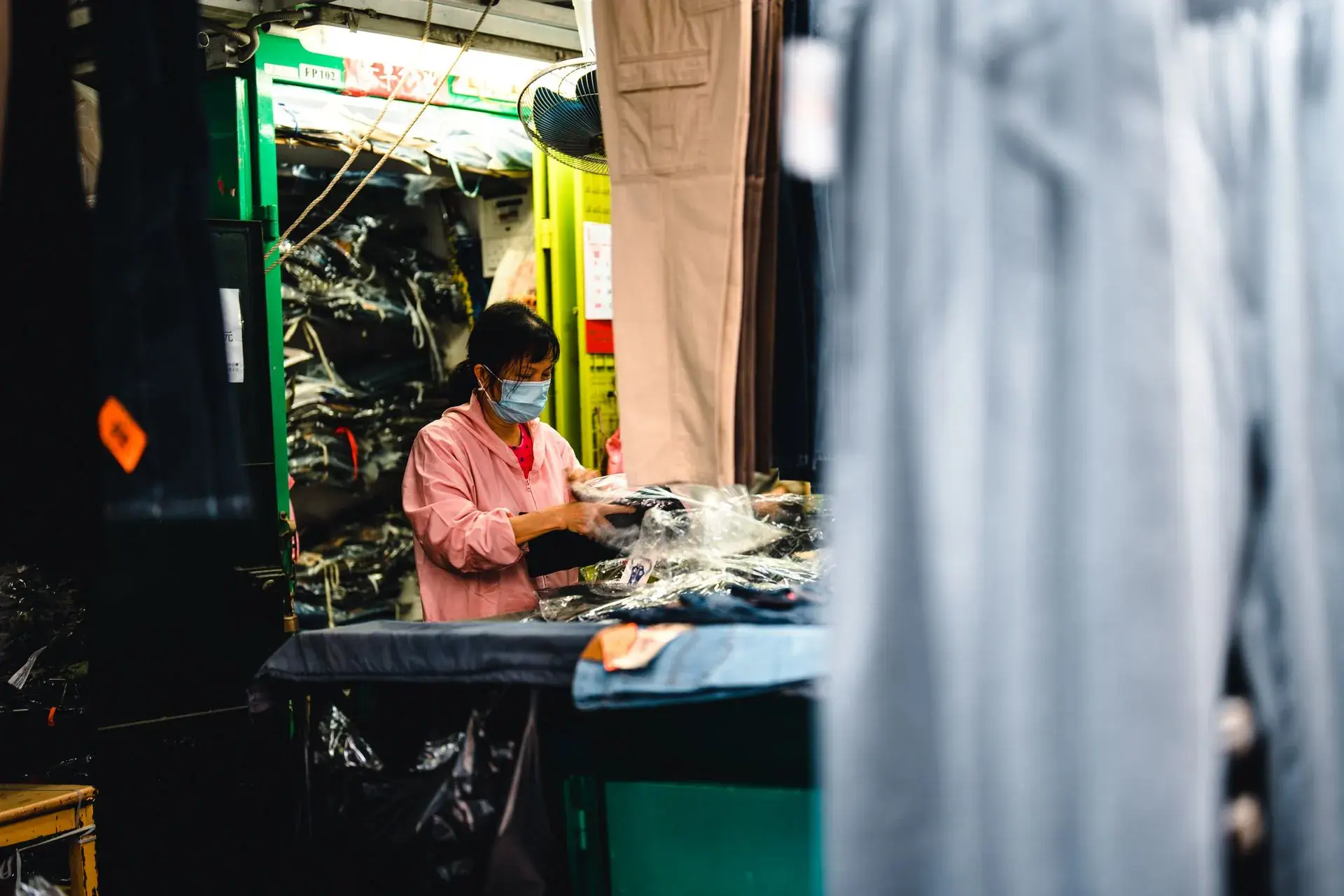 Worker packing finished garments into polybags at a packing table — stock illustration standing in for Finished garments packed into polybags at Lahajam, Lahore